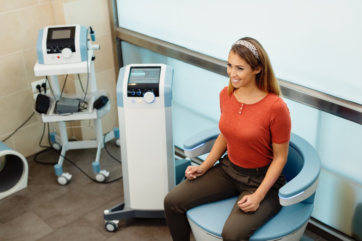 A female patient sits in an electromagnetic chair to strengthen her pelvic floor muscles