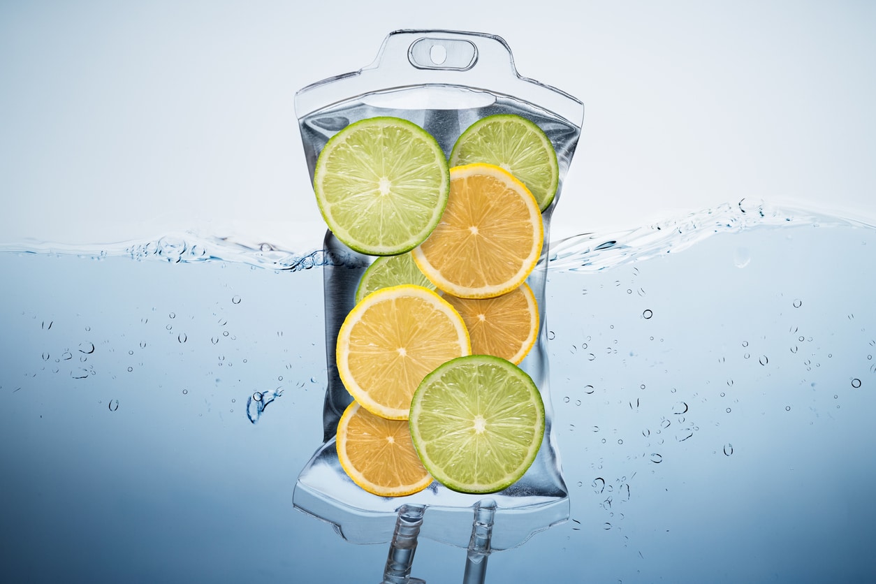 An IV bag filled with liquid and slices of citrus fruits floats in a refreshing pool of water